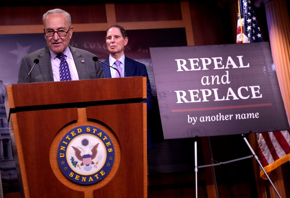 Senate Minority Leader Charles Schumer speaking at a podium next to a sign that says