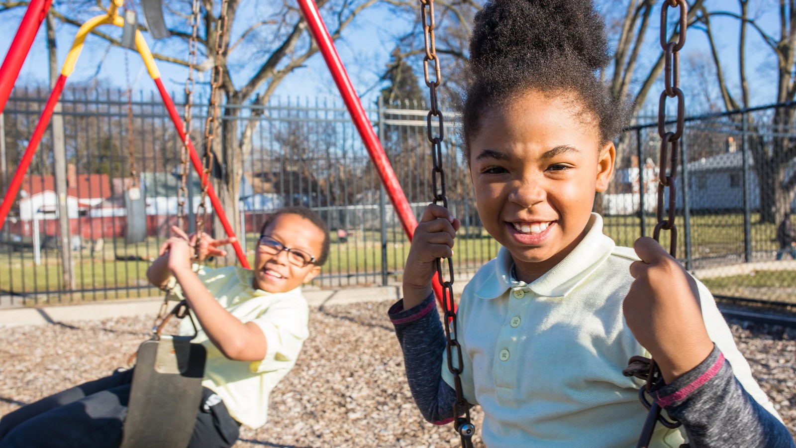 Two young children on swings in an outdoor playground