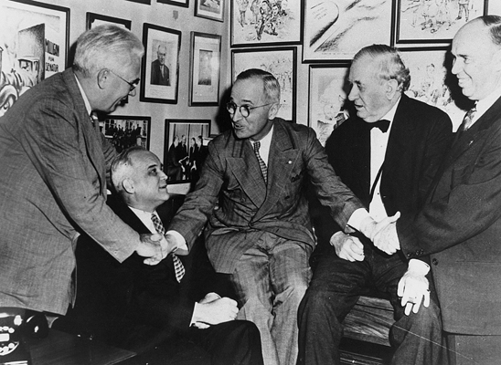 Black and white photo of President Truman huddled with four senators. 