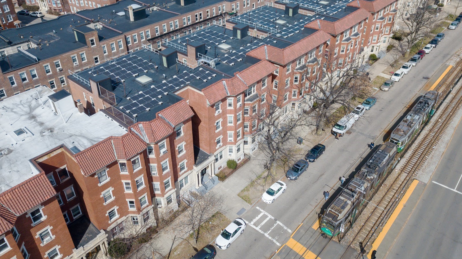 Overhead view of apartments with solar panels and a train nearby.